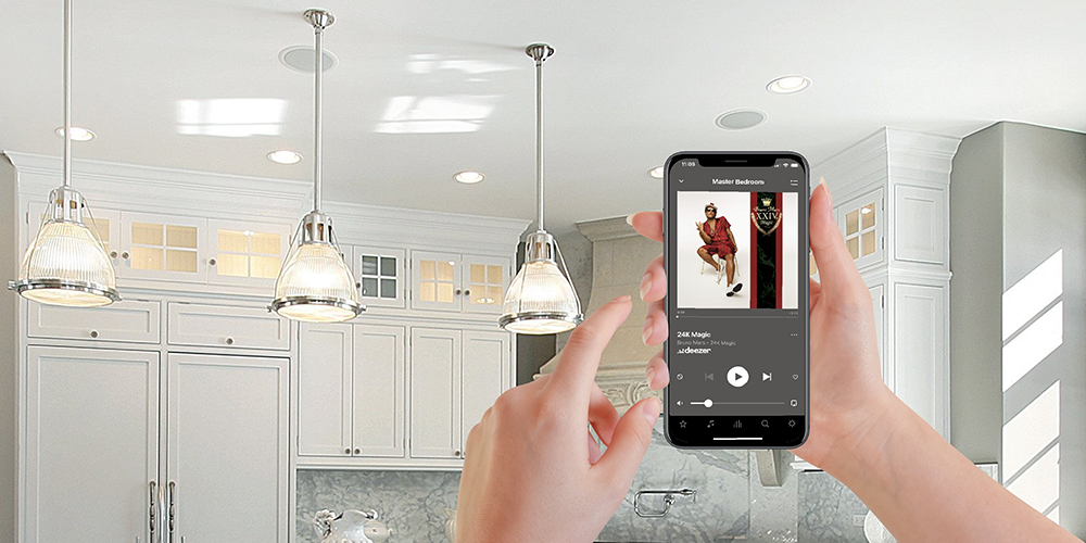 hands holding up a smart phone controlling built in ceiling speakers