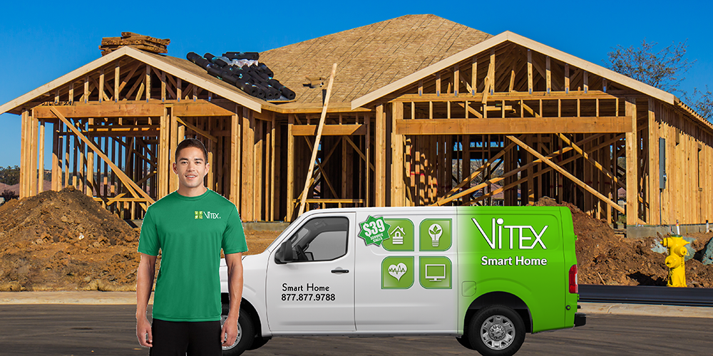 home automation installer standing in front of his commercial vehicle in fron ot a home that is being built